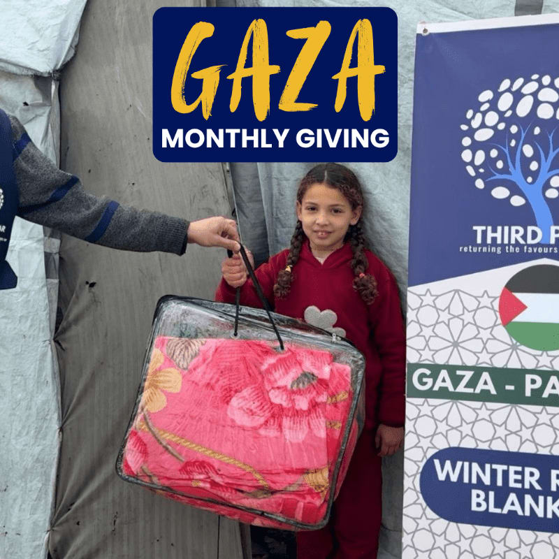 A young girl in a red outfit receives a blanket from a person in the foreground, with a banner for "Gaza Monthly Giving" and "Winter Relief Blankets" in the background.