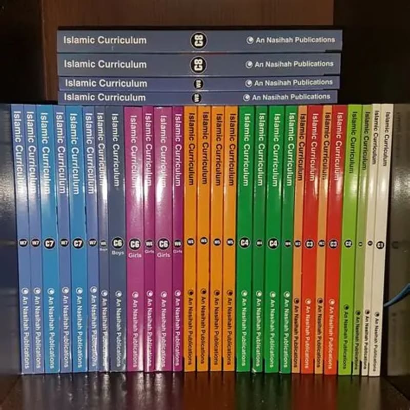 A large collection of "Islamic Curriculum" books from "An Nasihah Publications" are neatly stacked in the foreground, with a few more books of the same series stacked behind them in the background.