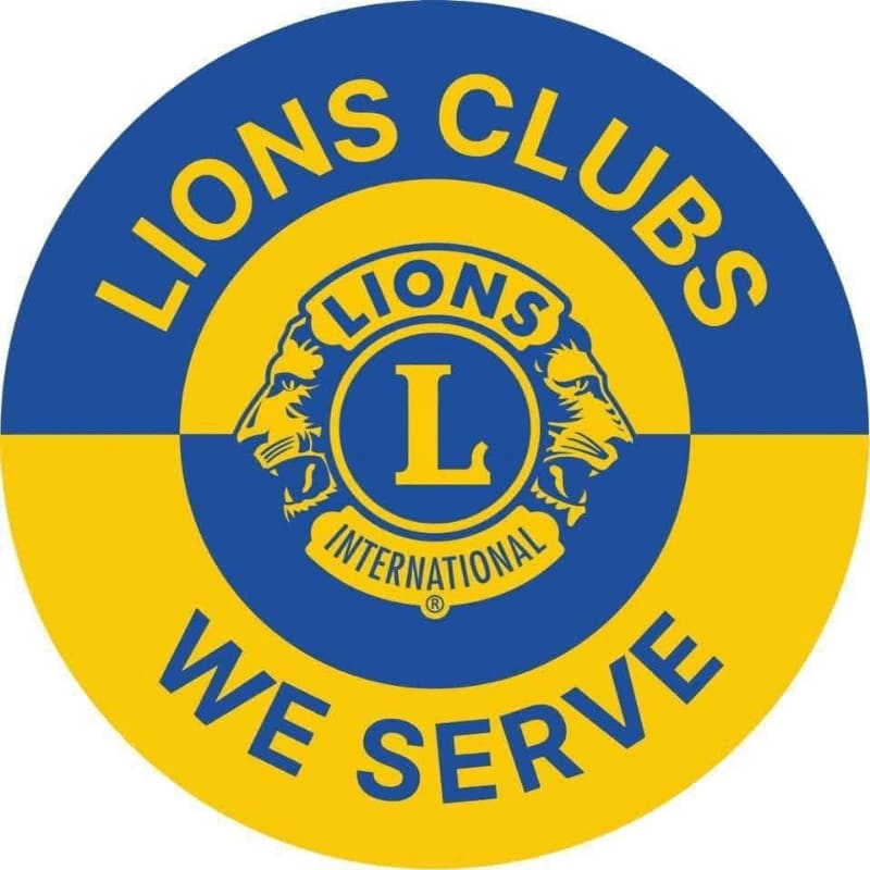 A circular logo with a blue and yellow background features the text "LIONS CLUBS" at the top and "WE SERVE" at the bottom, with a central emblem of two lions' heads surrounding a circle containing "LIONS INTERNATIONAL."