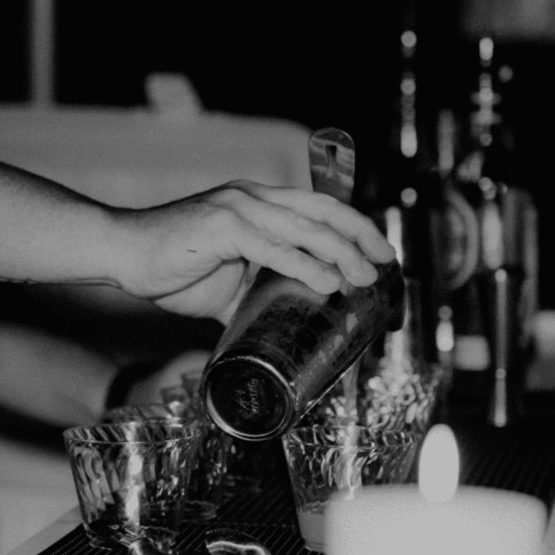 a person pouring a drink at a bar