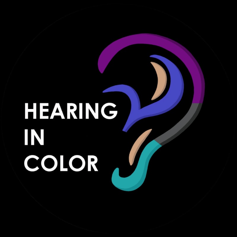 A stylized ear with colorful abstract shapes representing sound is set against a black background, with the words "HEARING IN COLOR" to its left.