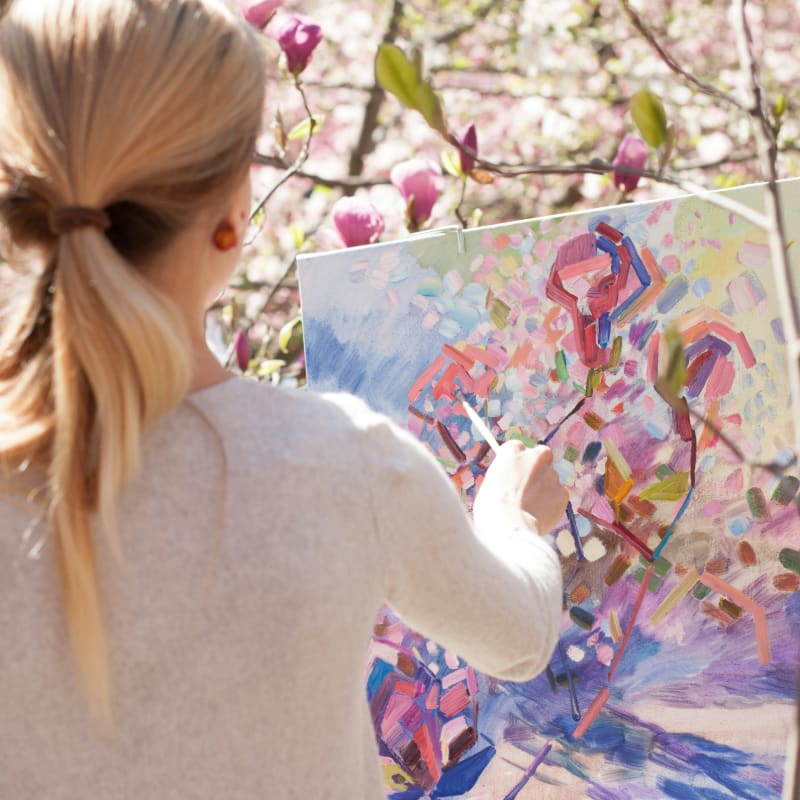 woman in white long sleeve shirt holding white and blue floral painting