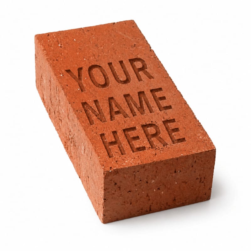 A red brick with "YOUR NAME HERE" carved into it rests on a plain white background.