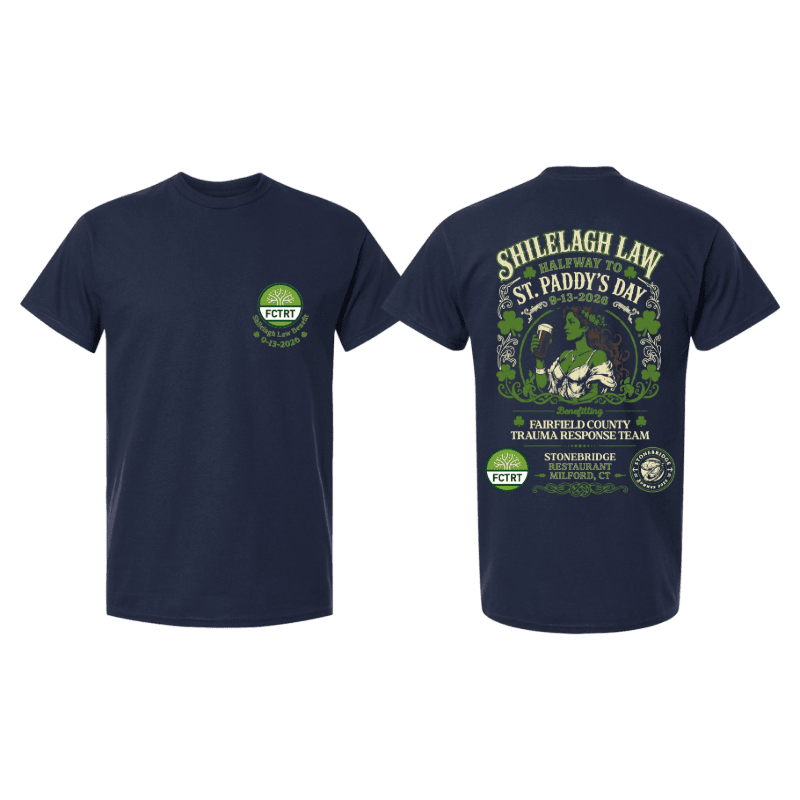 A navy blue t-shirt displays a St. Patrick's Day themed graphic on the back, featuring a leprechaun and shamrocks, with the front showing a smaller circular logo.