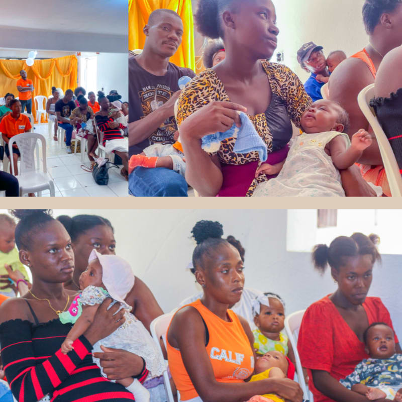 In the foreground, several women hold babies while seated, and in the background, a group of people are gathered in a room with decorations.