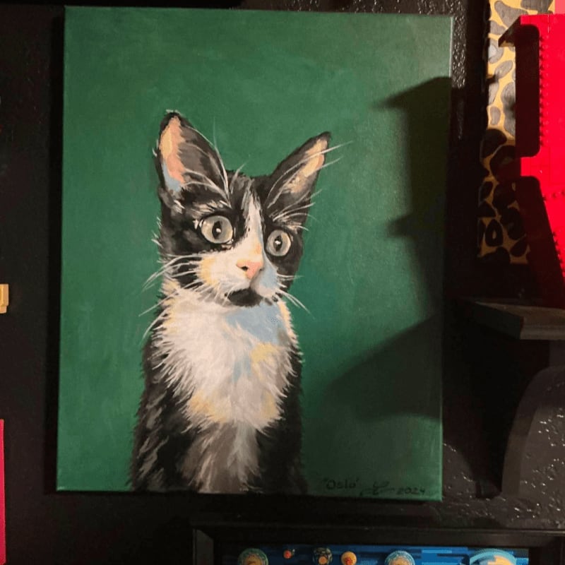A black and white cat with wide eyes is painted against a solid green background.