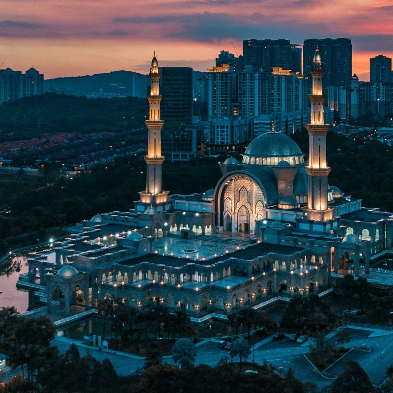 Masjid Wilayah Persekutuan in Kuala Lumpur under a warm orange sky at low sun
