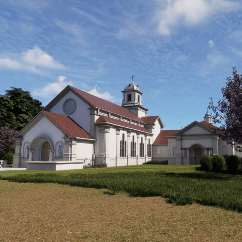 A white church with a red roof stands on a grassy hill under a blue sky with fluffy clouds, with trees and bushes surrounding it.
