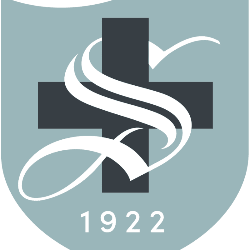 A dark gray cross with a white stylized "S" superimposed on it is centered against a light gray shield background, with the year "1922" displayed at the bottom.