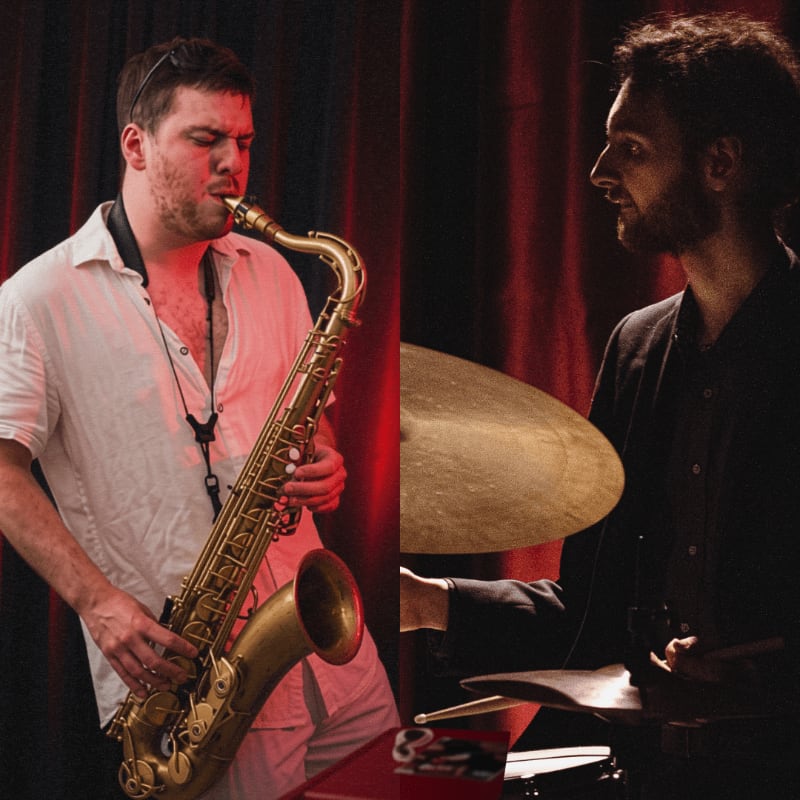 A man plays a saxophone in the foreground on the left, while another man plays drums in the foreground on the right, both against a dark red curtain background.