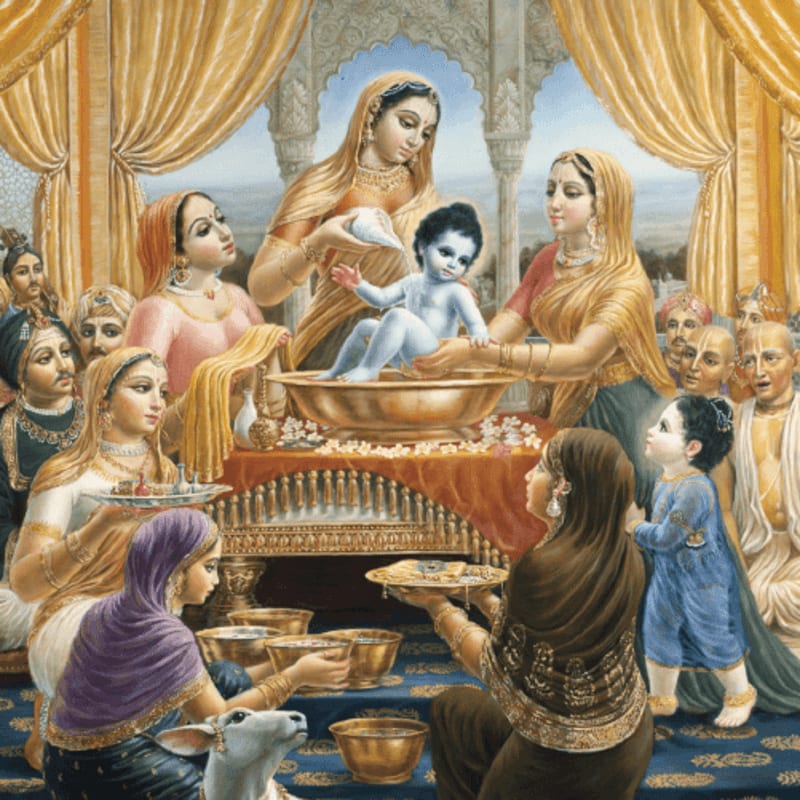 A blue-skinned infant is being bathed in a golden basin by several women in ornate clothing, while others look on and a small cow stands in the foreground, all within a richly decorated hall.