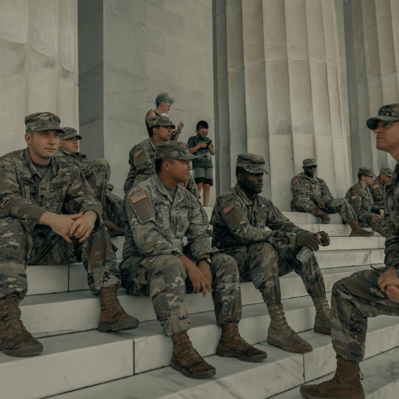 men in camouflage uniform standing near white wall