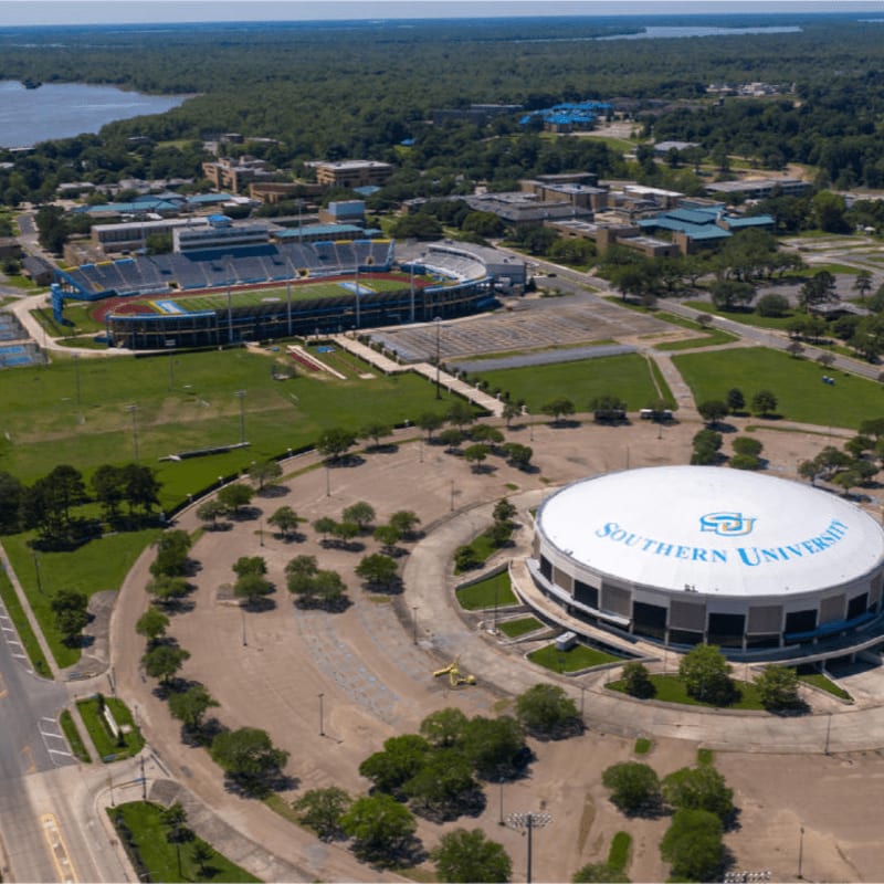 A large, domed arena with "Southern University" written on it sits in the foreground, while a stadium and a body of water are visible in the background.