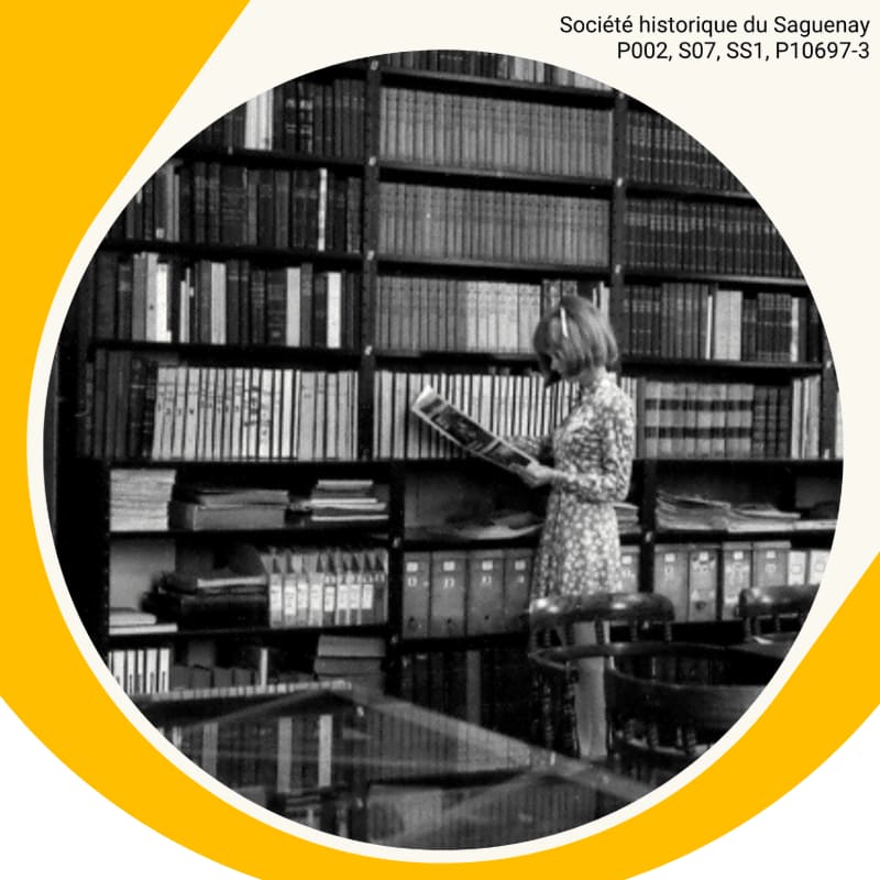 A woman in a floral dress stands reading a book in front of towering bookshelves filled with volumes, with a reflective table in the foreground and a yellow circular frame around the scene.