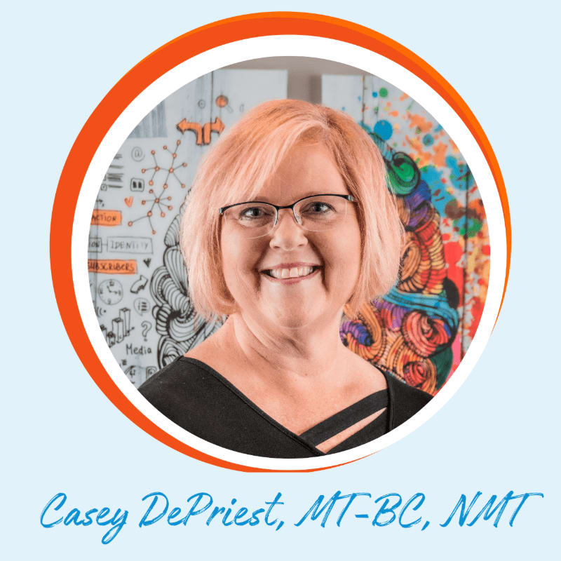 A smiling woman with short, pinkish hair and glasses is framed by an orange circle, with a colorful, abstract mural and a whiteboard with diagrams in the background.