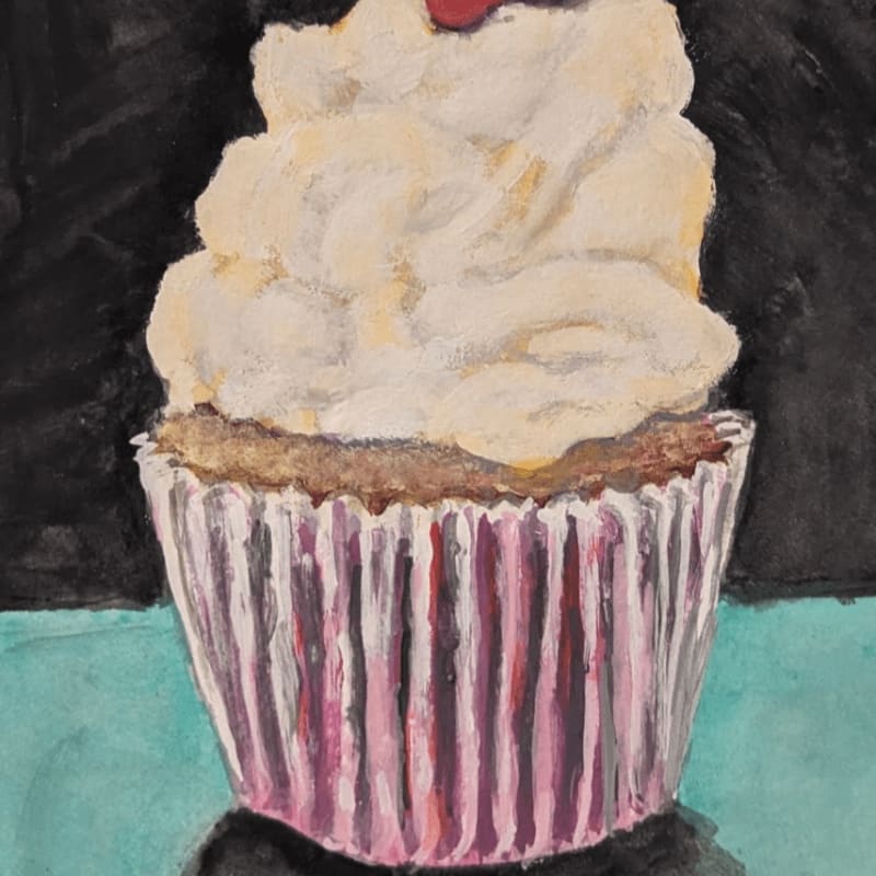 A cupcake with white frosting and a cherry on top sits in a pink striped wrapper against a dark background.