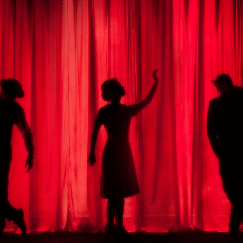 silhouette of three performers on stage