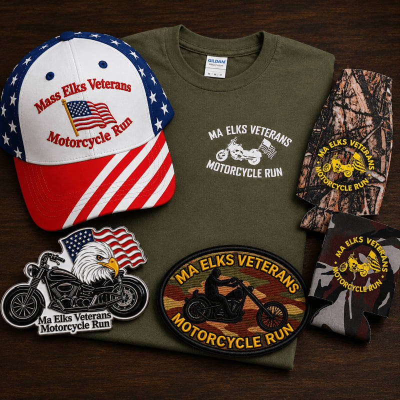 A patriotic baseball cap and t-shirt are displayed with motorcycle-themed patches and koozies on a wooden surface.