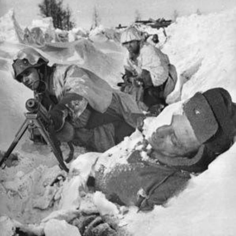 In the foreground, soldiers in winter camouflage man a machine gun next to a fallen comrade in the snow, while the background shows a desolate, snow-covered landscape with sparse trees.
