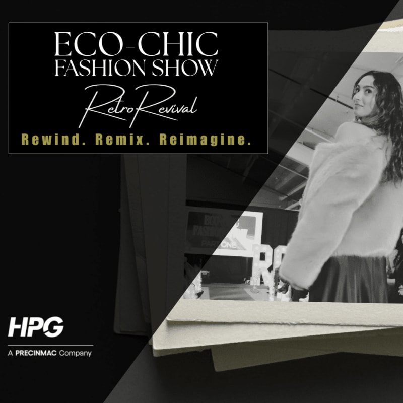 A woman in a fluffy white coat walks down a runway in front of a black and white backdrop with event details and a company logo.