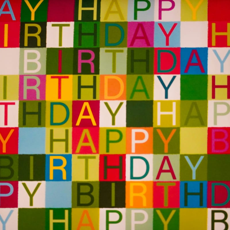 Colorful birthday text pattern on checkered background