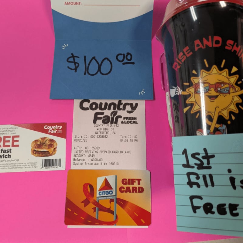 A $100 gift card and receipt are in the foreground, with a cup and a coupon in the background.