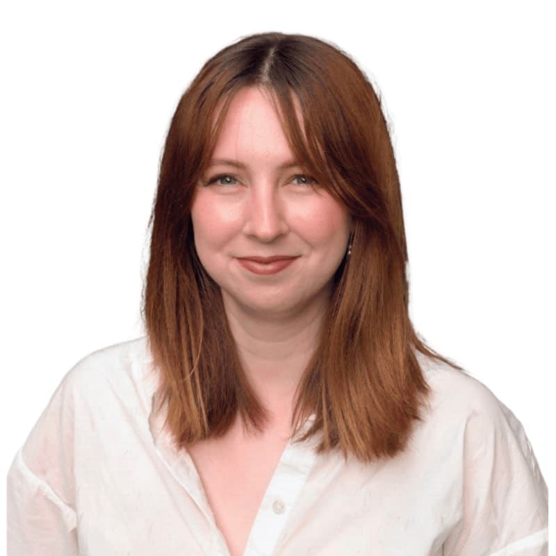 A woman with auburn hair and a white shirt smiles against a plain white background.