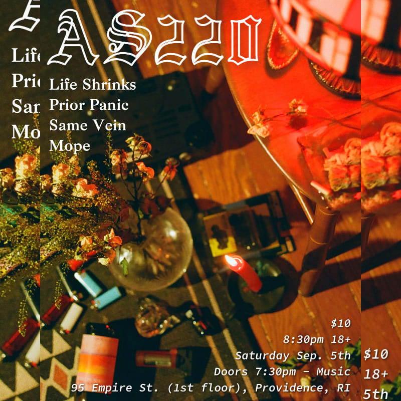In the foreground, a collection of candles, lighters, and a vase of flowers are arranged on a patterned surface, while the background features a red, circular object with a plate of sushi and event details for AS220.