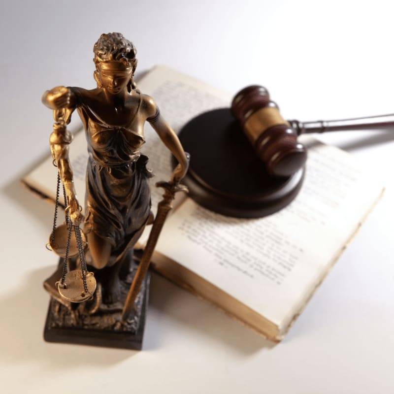 Statue of justice, gavel, and open book on table