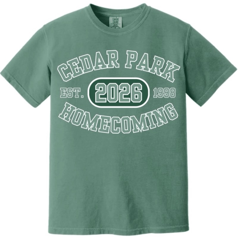 A green t-shirt with "CEDAR PARK 2026 HOMECOMING" printed on it is displayed against a plain white background.
