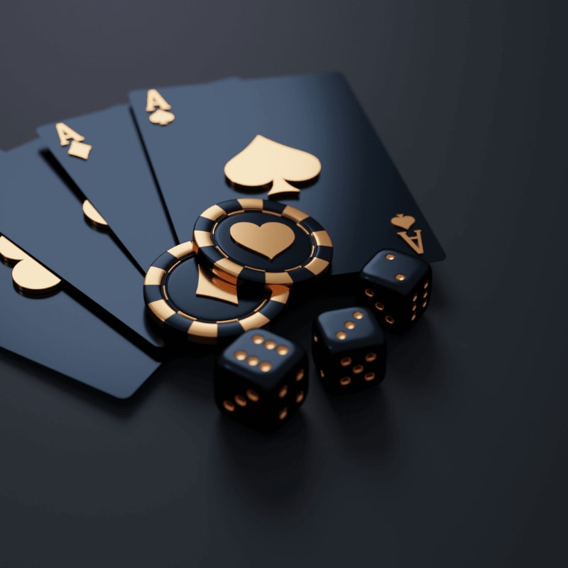 Black playing cards with gold aces, poker chips, and dice on dark surface