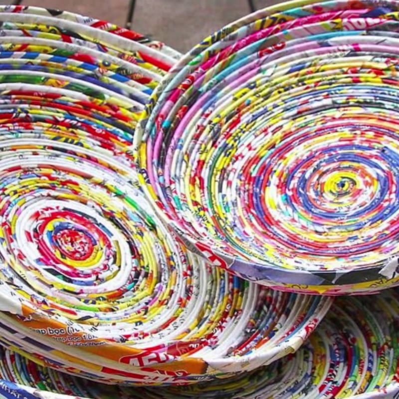 Colorful, coiled paper bowls are stacked in the foreground, with a blurred wooden surface in the background.