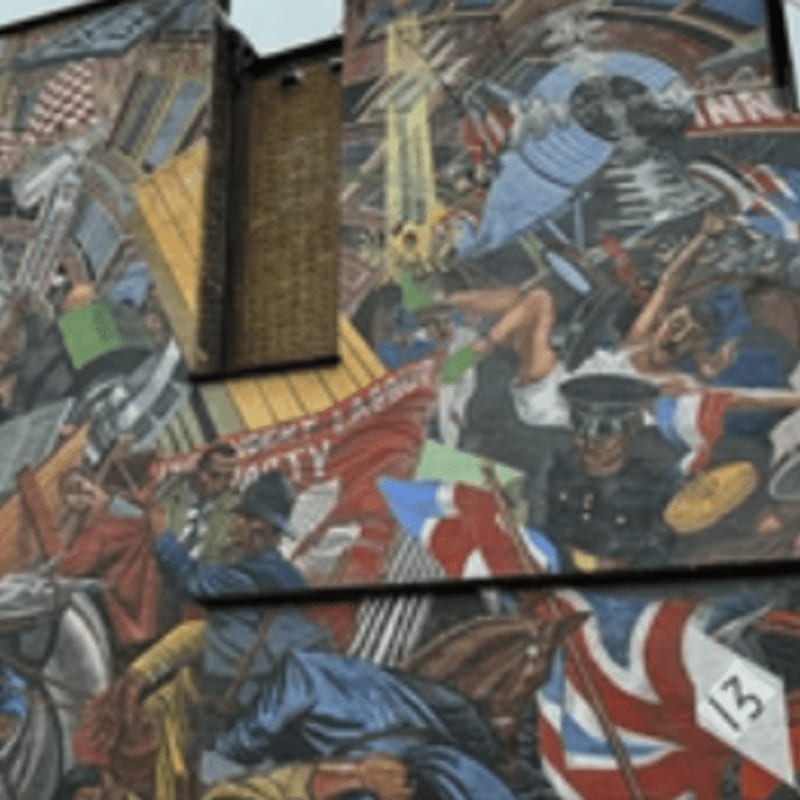 A vibrant mural fills the frame, depicting a chaotic scene of figures in historical attire and flags in the foreground, set against a brick building in the background.