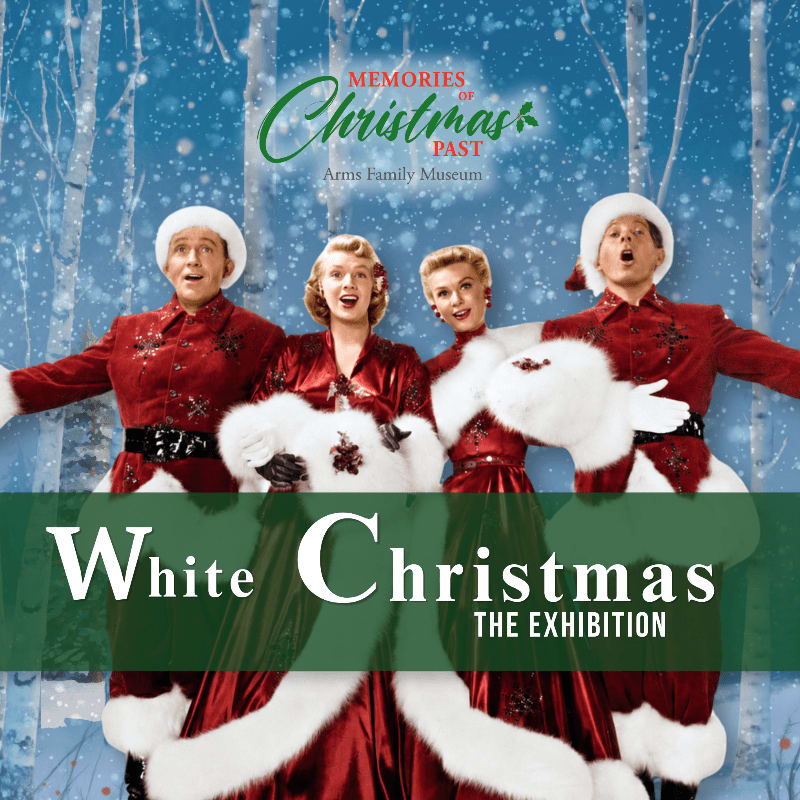 Four performers in festive red and white costumes sing in front of a snowy forest backdrop, with "White Christmas THE EXHIBITION" text overlaying the bottom.