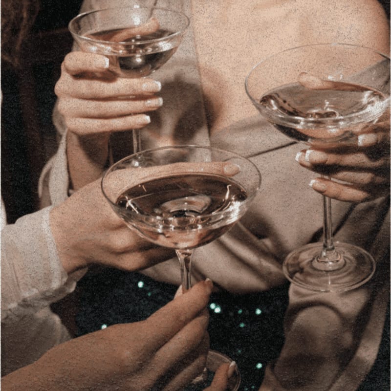 Hands clink champagne glasses in the foreground, with a blurred, sparkly background.