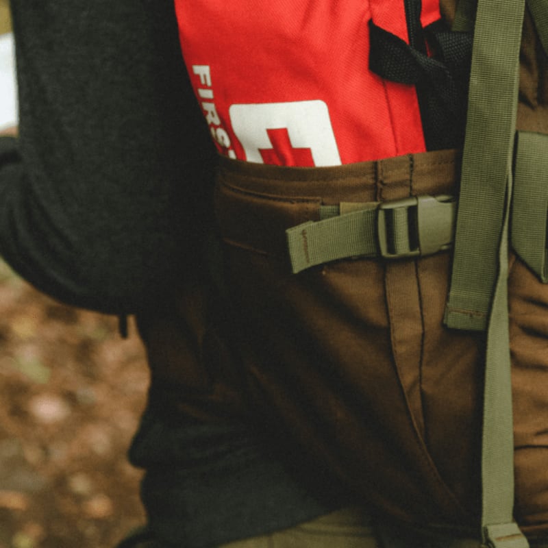 man in red and black shirt and brown pants with black backpack