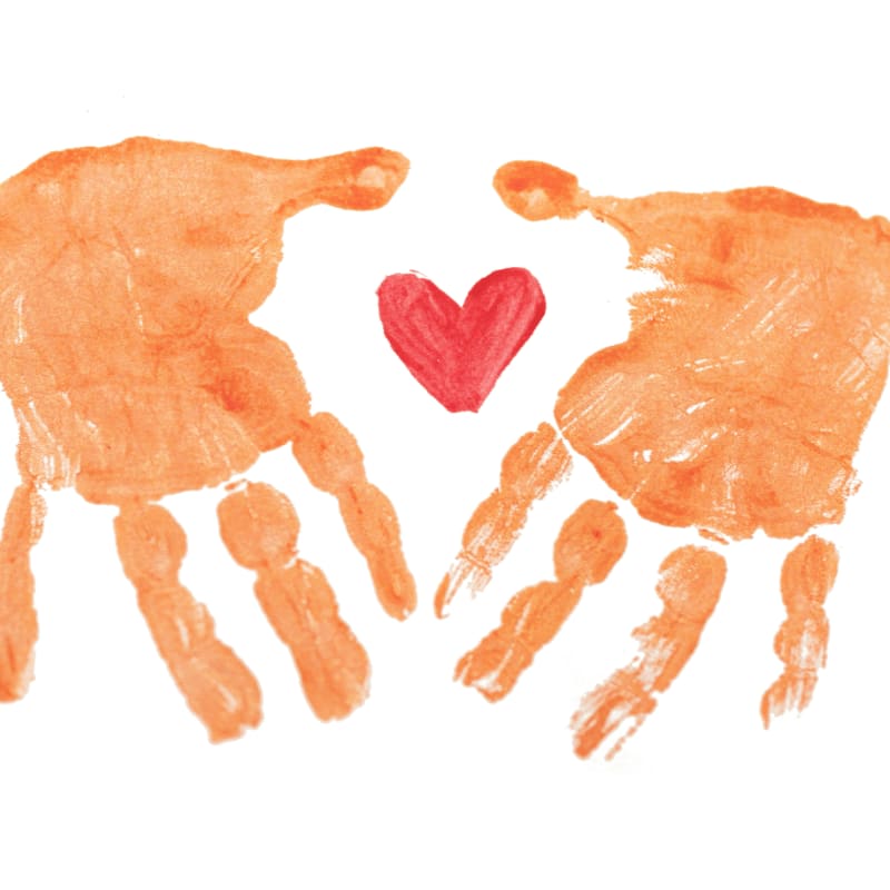 Two orange handprints facing each other with a small red heart between them