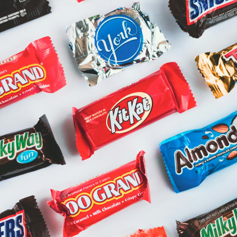 a variety of candy bars lined up on a white surface