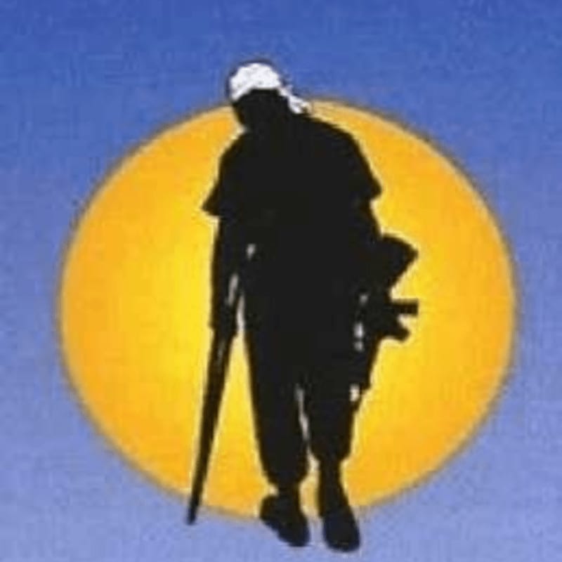 A silhouetted figure with a cane and a rifle walks in front of a large, bright yellow circle against a blue sky.