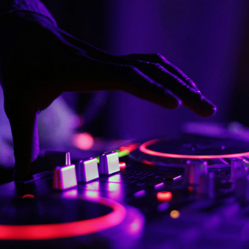 selective focus silhouette photography of man playing red-lighted DJ terminal