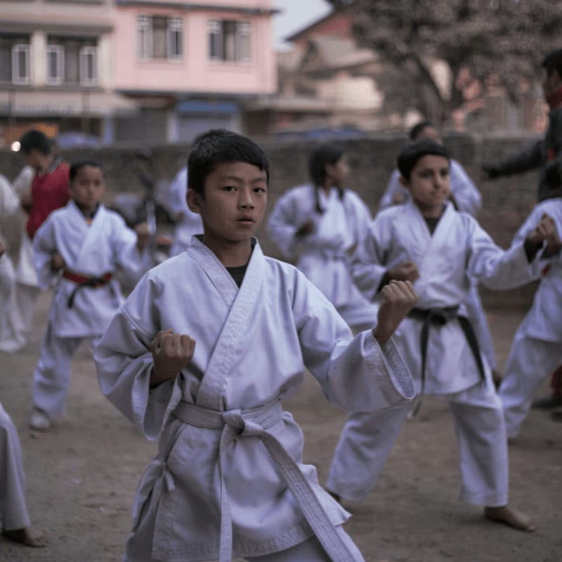 boy in white robe holding a stick