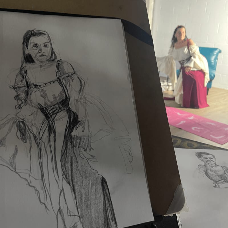 A charcoal sketch of a woman in historical dress is in the foreground, while a woman in a similar costume sits on a blue chair in the background.