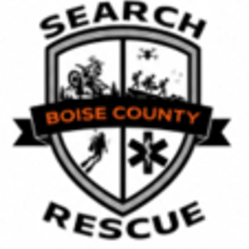 A shield with "SEARCH" and "RESCUE" above and below, featuring scenes of a motorcycle, drones, hikers, a diver, and a medical symbol, with "BOISE COUNTY" emblazoned across a banner in the center.