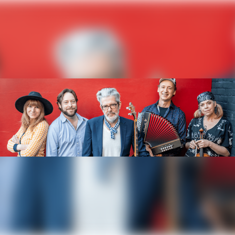 Five musicians, two holding instruments, stand against a blurred red background.