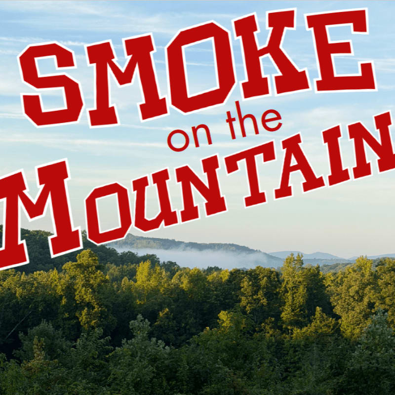 Red text reading "SMOKE on the MOUNTAIN" hovers over a lush green forest in the foreground, with a misty mountain range visible in the background under a blue sky.