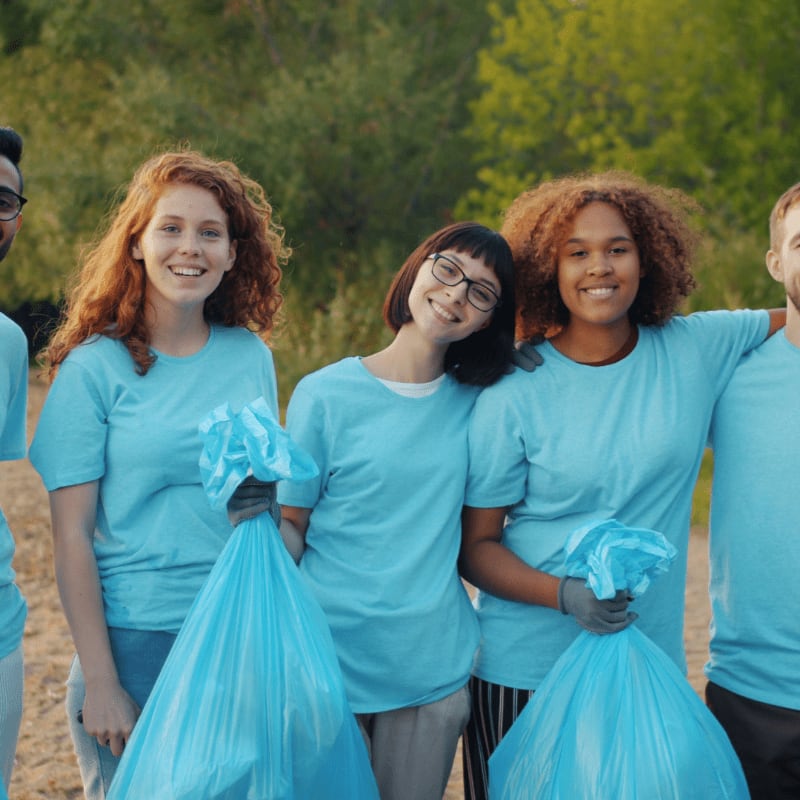 Diverse group of volunteers holding trash bags outdoors