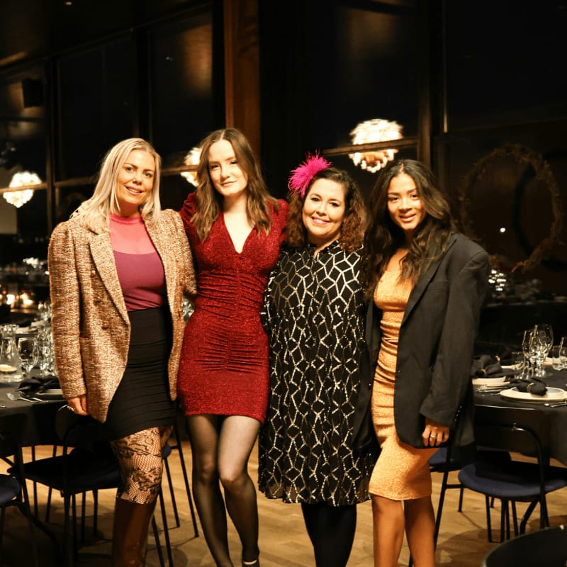 Four women posing at a formal event