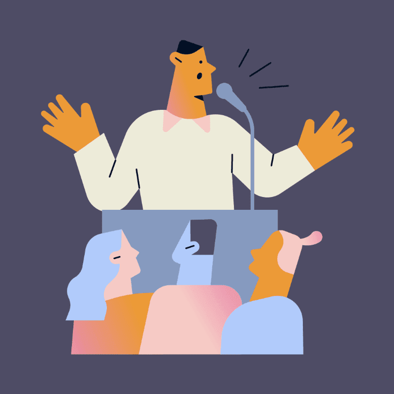 A speaker gestures with open hands at a podium in front of a microphone, while an audience watches from below against a solid background.