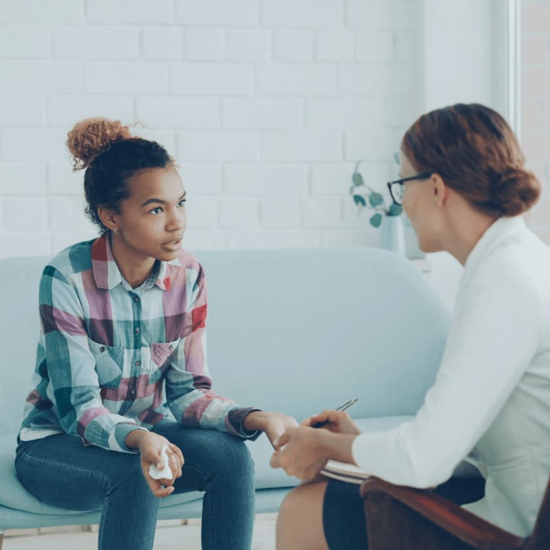 Therapist talking to a young woman on couch