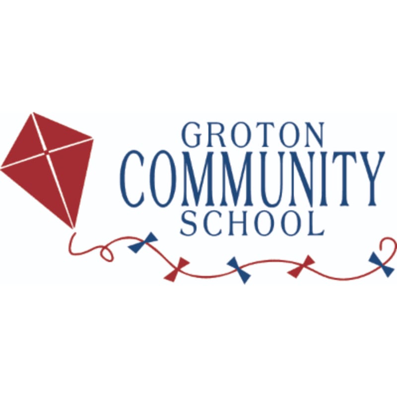 A red kite with a decorative string flies in front of the words "GROTON COMMUNITY SCHOOL" on a white background.